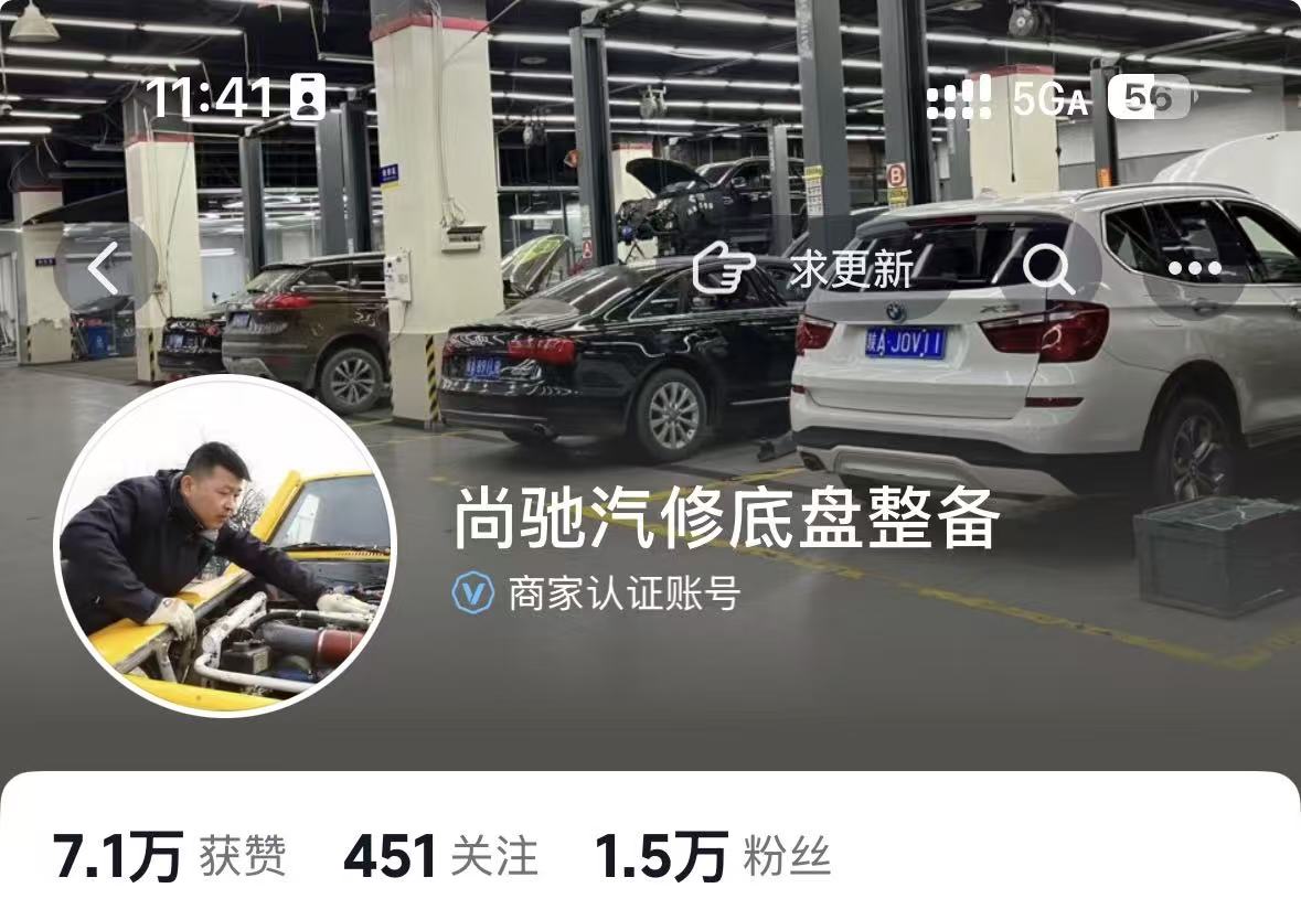 三十岁左右男性技师在明亮汽修店内工作,身穿蓝色工装,正在维修一辆白色轿车,工具整齐摆放,环境整洁有序